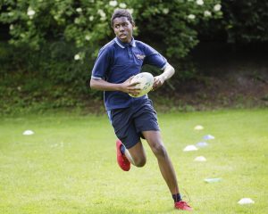 child running with a rugby ball