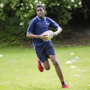 child running with a rugby ball