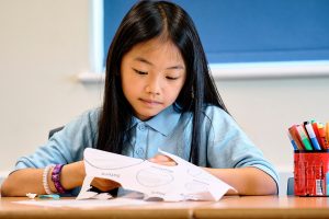 girl cutting out drawings on paper