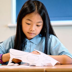 girl cutting out drawings on paper